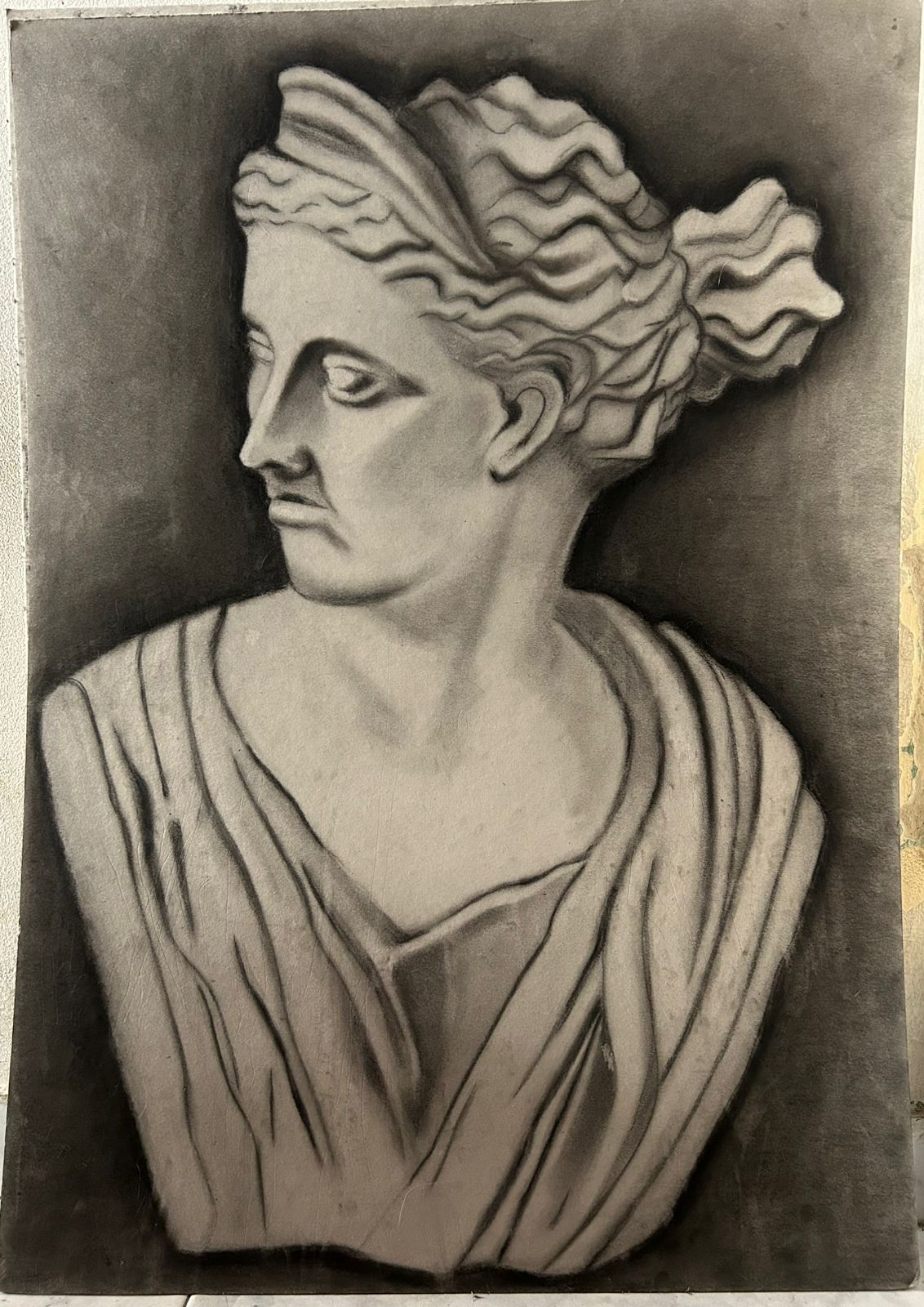 Dibujo a carboncillo de un busto escultórico clásico, con la cabeza girada de perfil.
