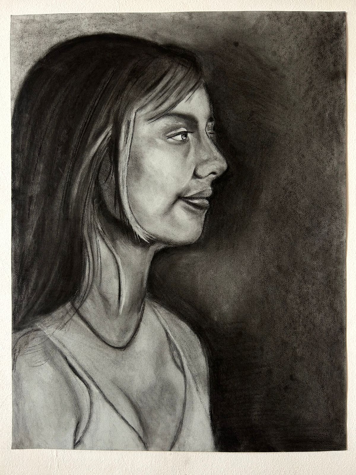 Retrato a carboncillo de una mujer de perfil, con cabello largo y oscuro.